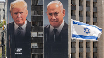 Israeli workers hang on the facade of a building giant posters by the Yesha Council, an umbrella organization of municipal councils of Jewish settlements in the West Bank, depicting the faces of (L to R) US President Donald Trump and Israeli Prime Minister 