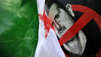 A Free Syria's flag is seen next to a poster of Syrian President Bashar al-Assad during a demonstration held in front of the Fatih mosque in Istanbul on May 24, 2013