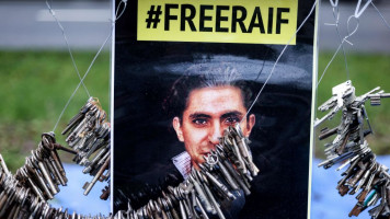 A poster calling for Raif Badawi to be freed. Keys are suspended on wires around it