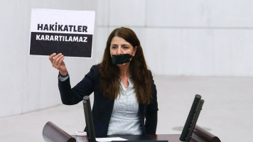 Turkish politician Zuleyha Gulum holds a sign reading 'Truths cannot be obscured' in parliament