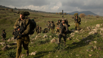 Soldiers walk on stony terrain