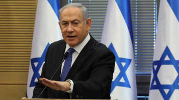 Benjamin Netanyahu in front of three Israeli flags