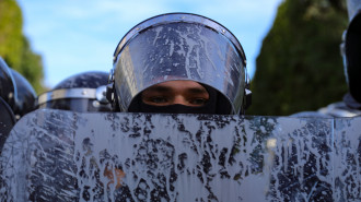 A Tunisian police officer's shield and helmet are covered with a liquid sprayed by protesters during a demonstration to protest against police repression in January 2021. [Getty]