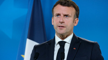 Emmanuel Macron speaking in front of a French flag