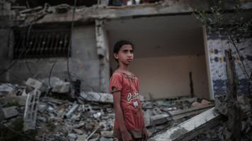 A child stands in front of a destroyed building targeted by Israeli attacks in Beit Hanoun, Gaza on 29 May 2021. [Getty]