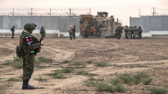 Russian soldier watches Turkish military convoy, Hasakeh, Syria