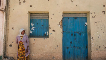 A woman leans on the wall of a damaged house which was shelled as federal-aligned forces entered the city, in Wukro, north of Mekele, on 1 March 2021. [Getty]