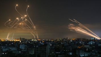 The Israeli Iron Dome missile defence system (L) intercepts rockets (R) fired by the Hamas movement on 14 May 14 2021. 