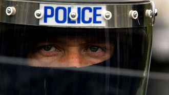 A Royal Ulster Constabulary (RUC) riot police officer looks out from behind his face shield 30 June, 2001 in Belfast, Northern Ireland.