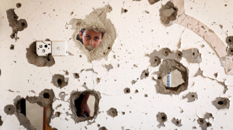 A photo taken on March 18, 2018, shows a Yemeni child looking out from behind a wall that was damaged in an air strike in the southern Yemeni city of Taez. [Getty]