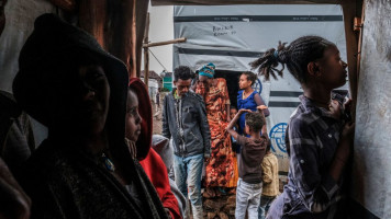 Internally displaced people protect themselves from the rain at a camp in the town of Azezo, Ethiopia, on July 12, 2021. The camp hosts Ethiopians as well as Eritrean refugees uprooted by the ongoing war in the region of Tigray. 