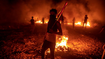 Palestinian protesters take part in a night demonstration near the fence along the border with Israel, east of Gaza City on 28 August 2021 in Gaza City. [Getty]