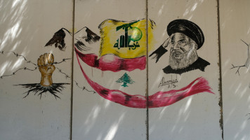 A picture of Hezbollah Secretary General Sayyed Hassan Nasrallah along with the flag of the movement is seen on a section of the 11km concrete wall built by Israelis in 2018 in southern Lebanon. [Getty]