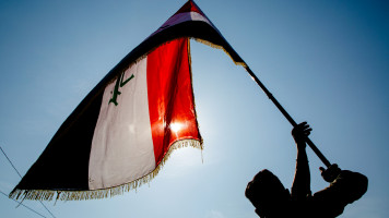 An Iraqi student waves his country's national flag during anti-government protests in the southern Iraqi city of Basra on January 28, 2020