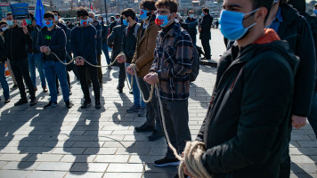 Members of the Muslim Uighur minority keep symbolically their hands tied with a rope as they demonstrate to ask for news of their relatives [Getty Images]