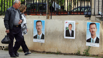 A Lebanese couple looks at pictures of former pro-Syrian president Emile Lahoud (C) and Syrian President Bashar al-Assad plastered in the morning on a wall in Beirut on May 9, 2008 [Getty Images]