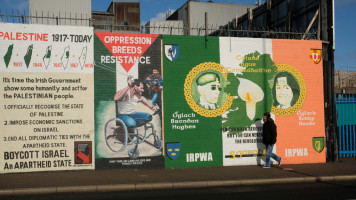 A man passes by a mural with images of Bobby Sands and Brendan Hughes painted on the wall in Falls Road on October 29, 2019 in Belfast, United Kingdom [Getty Images]