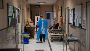 An Iranian doctor wearing a protective suit walks along a corridor at a new coronavirus (COVID-19) section of the Firoozabadi hospital in the Shahre-Rey neighbourhood in southern Tehran on June 20, 2020 [Getty Images]