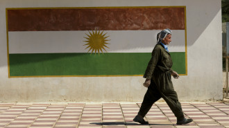 A Kurdish man wearing traditional clothes walks past a Kurdish flag painted onto a wall in Erbil the capital of the Northern region of Iraq