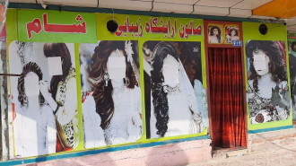 Afghan beauticians paint over large photos of women on the doors of beauty salons after Taliban control across the country in Nangarhar, Afghanistan [Getty Images]