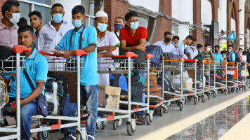 Dozens of migrant workers queue outside the Dhaka airport before their flight to Saudi Arabia. Many of the workers going to Saudi Arabia were unable to board their plane as they did not receive the second dose of a covid-19 vaccine [Getty Images]