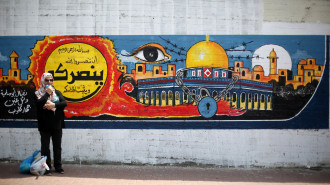 A Palestinian woman stands in front of a mural for the city of Jerusalem in Gaza City