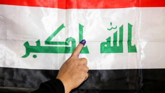 An Iraqi woman shows her ink-stained index finger before a national flag after having cast her vote in the first parliamentary election since declaring victory over the Islamic State (IS) group, in the capital Baghdad's Karrada district on May 12, 2018