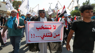 Iraqi protester holds sign saying "Don't vote for who killed me"