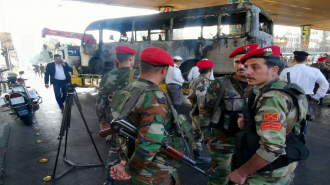 Syrian soldiers stand near charred bus