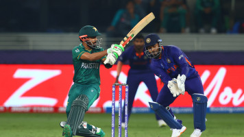 Babar Azam of Pakistan plays a shot as Rishabh Pant of India looks on during the ICC Men's T20 World Cup match between India and Pakistan at Dubai International Stadium on October 24, 2021 in Dubai, United Arab Emirates. (Photo by Francois Nel/Getty Images)