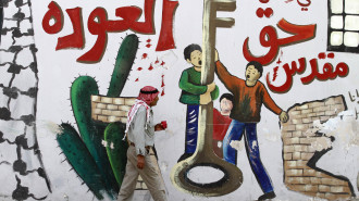 A Palestinian man walks past a mural on a wall in the West Bank city of Jenin reading in Arabic: "So that we don't forget the sacred right to return" on May 13, 2013