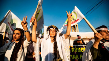 A Syrian Yazidi woman dressed in traditional clothing flashes the victory gesture while taking part in a demonstration in the northeastern town of Amude, about 28 kilometres west of Qamishli near the Syrian-Turkish border, on August 3, 2018