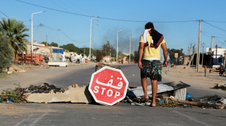 A Tunisian anti-government demonstrator stands in front of a road block during a general strike on November 10, 2021, following the reopening of a rubbish dump, in the Tunisian town of Agareb in the central region of Sfax, which has seen weeks of angry demonstrations over a growing waste crisis.