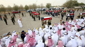 Kuwaitis watch as the coffins of nineteen Kuwaiti prisoners of war (POWs) whose remains were recently found in a mass grave in Iraq and identified following DNA tests, are carried by honour guards during a funeral procession at a cemetary in Kuwait City on November 21, 2021