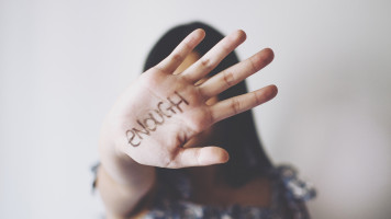 A woman holding her hand out with the word "enough" written on