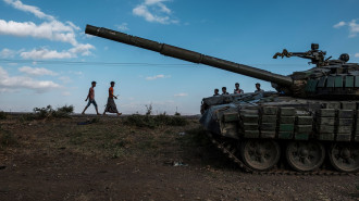 Youngsters walk next to an abandoned tank belonging to Tigrayan forces south of the town of Mehoni, Ethiopia, on December 11, 2020. 