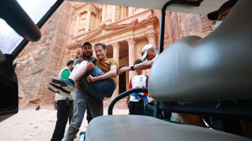 A man helps a disabled tourists to ride an electric cart, during his trip to Jordan's famed ancient city of Petra, some 230km (143 miles) south of the capital Amman, on October 27, 2021. 