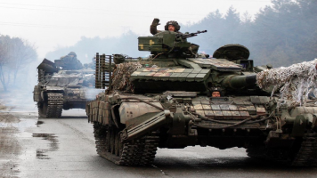 Ukrainian servicemen ride on tanks