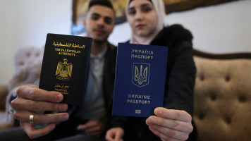 Ukrainian Viktoria Saidam (R), accompanied by her Palestinian husband Ibrahim Saidam, show their passports at their family home in the refugee camp of Bureij in the central Gaza Strip on March 22, 2022