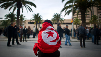 A woman, wearing a flag of Tunisia, demonstrates against Ben Ali's Constitutional Democratic Rally (RCD) in a new wave of anger about the presence of RCD stalwarts in the transitional government, on January 20, 2011, in Tunis. 