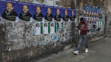 People pass by election campaign posters hung in the city of Beirut, on April 18, 2022 in Beirut, Lebanon. Billboards without advertisers, for lack of money, are plastered with political posters across Beirut. On May 15 Lebanese will be heading to polls for the first time since the financial collapse and the protest movement of 2019