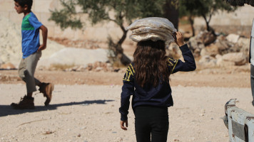 A girl carrying a bag of bread on her head [Hadia Al Mansour]