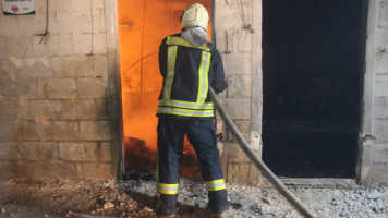 Firefighter outside door with flames inside