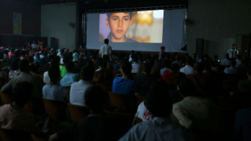 Palestinian families attend the screening of a movie during the opening of the "Red Carpet" cinema festival in Gaza City, on May 12, 2016