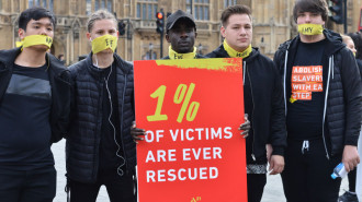 People marching against modern slavery through London wearing face masks representing the silence of modern slaves in forced labour and sexual exploitation