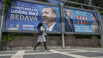 A Syrian woman walks past billboards showing President Erdogan and his main challenger, Kemal Kilicdaroglu [AFP]