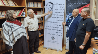 People standing next to a poster commemorating Yasser Arafat