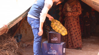 Man hands sack of potatoes to a woman in a tent