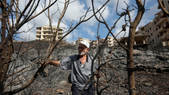 A Syrian man inspects a scorched area in the aftermath of a forest fire which ravaged swathes of land in the countryside of the western city of Tartus