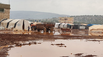 Muddy pool of water in front of a row of tents 